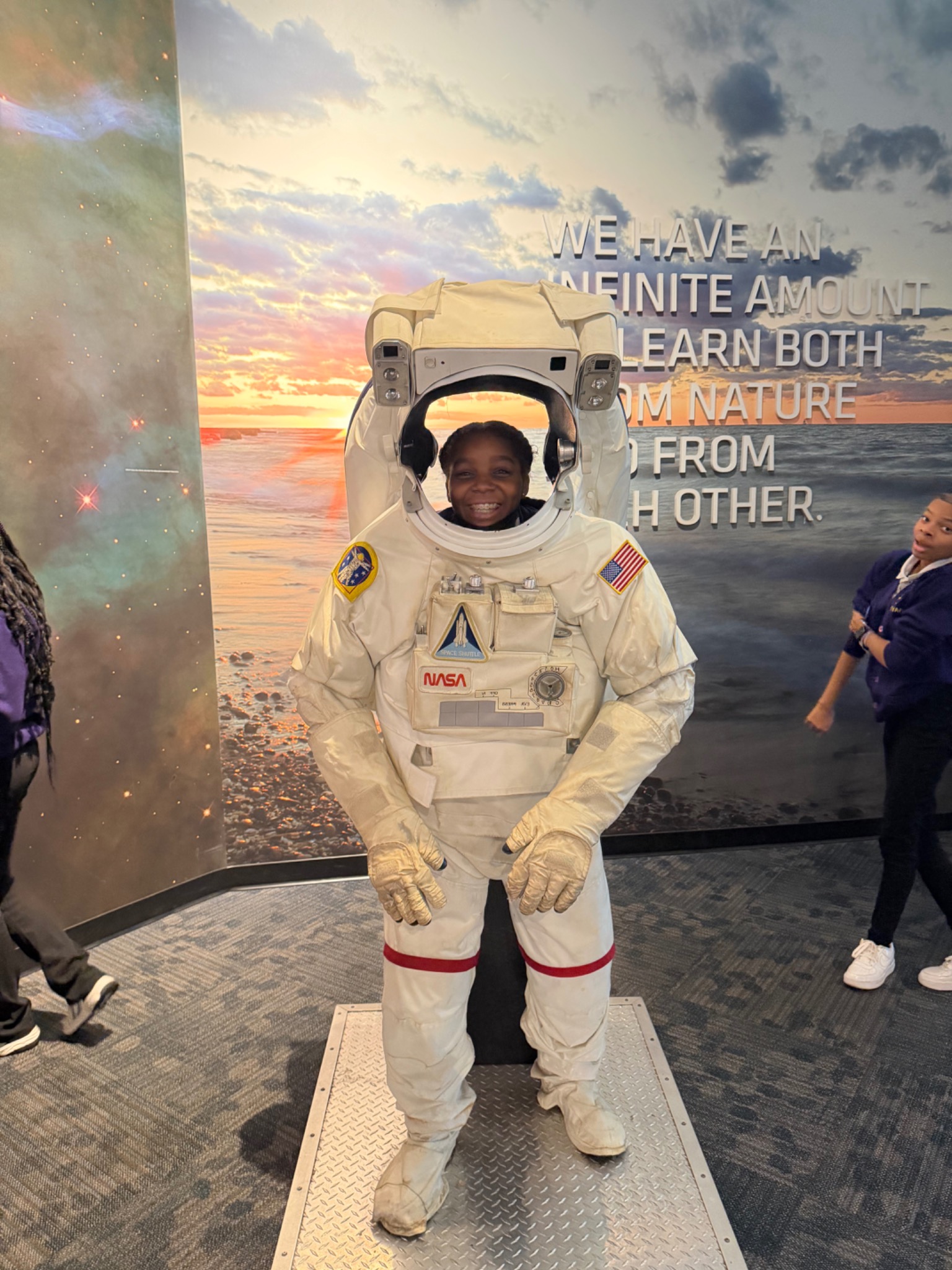 A smiling student trying an astronaut suit exhibit