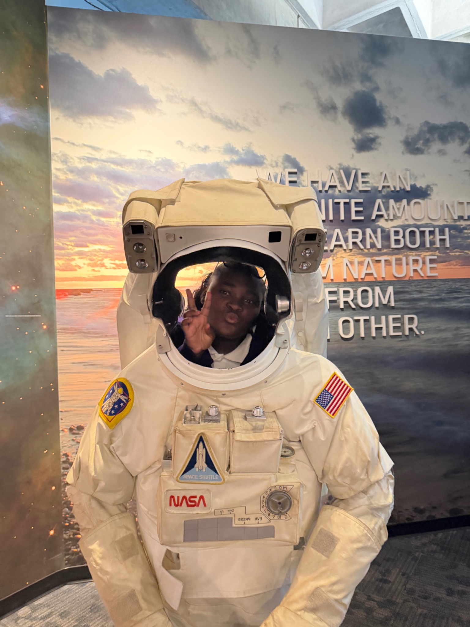 A student posing inside an astronaut suit exhibit